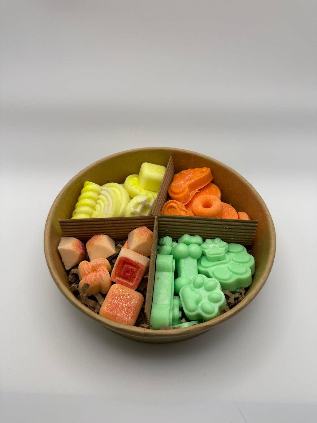 Round container of colorful wax melts on a white background