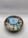 Round container of colorful wax melts on a white background