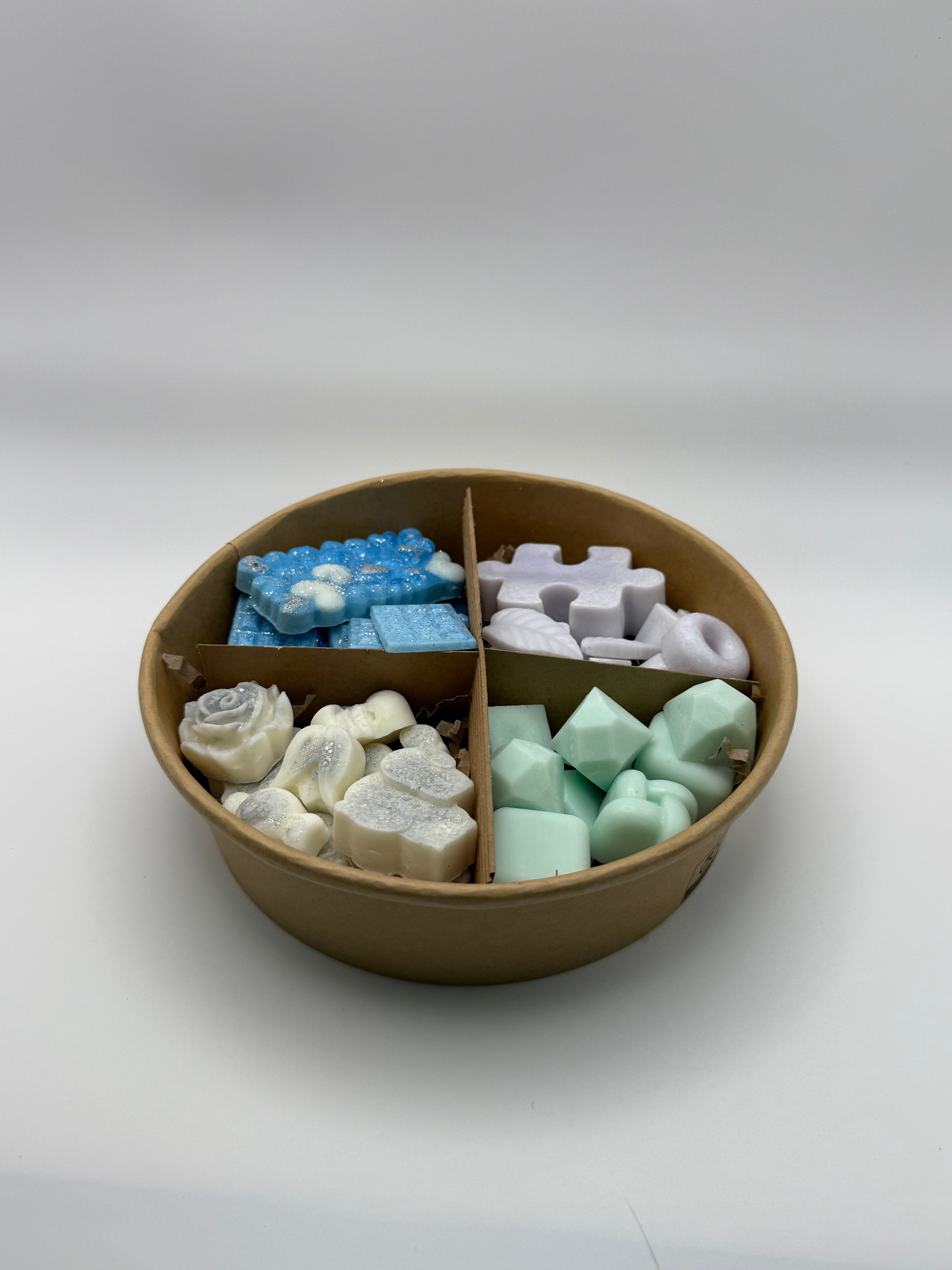 Round container of colorful wax melts on a white background