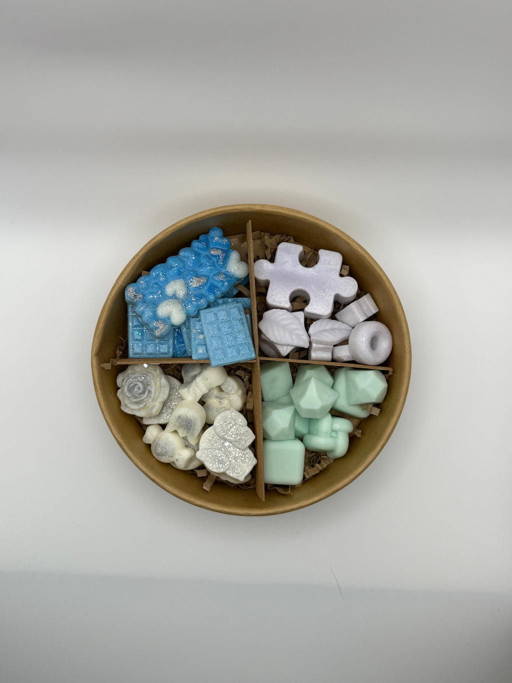 Round container of colorful wax melts on a white background