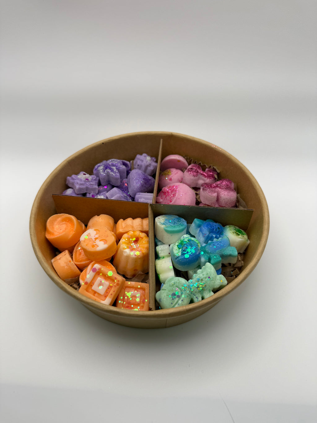 Round container of colorful wax melts on a white background