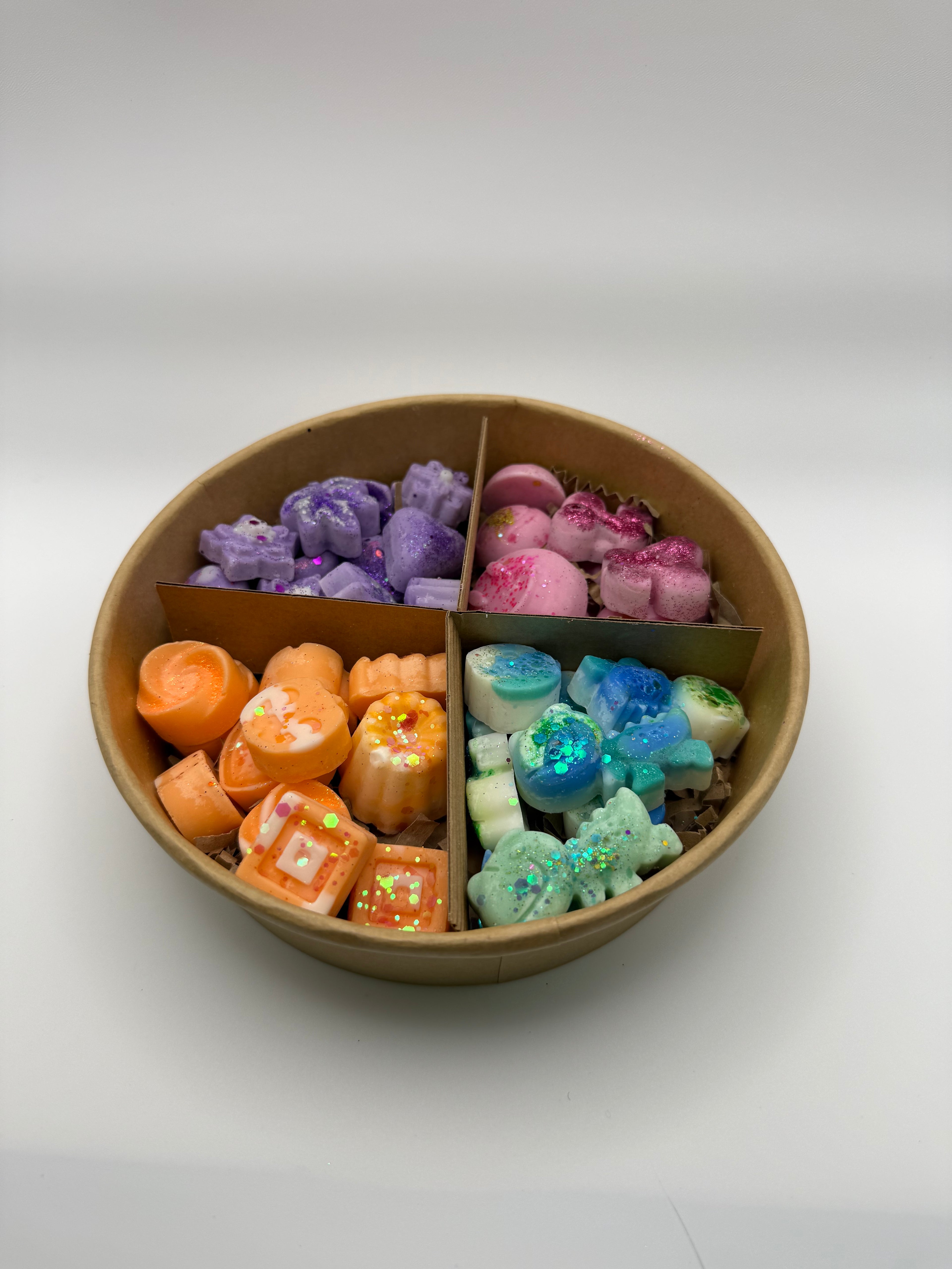Round container of colorful wax melts on a white background