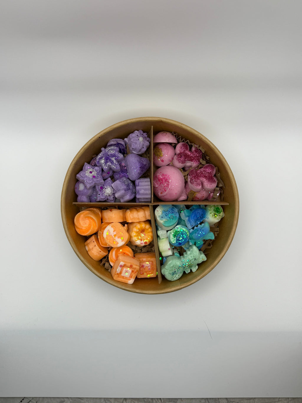 Round container of colorful wax melts on a white background