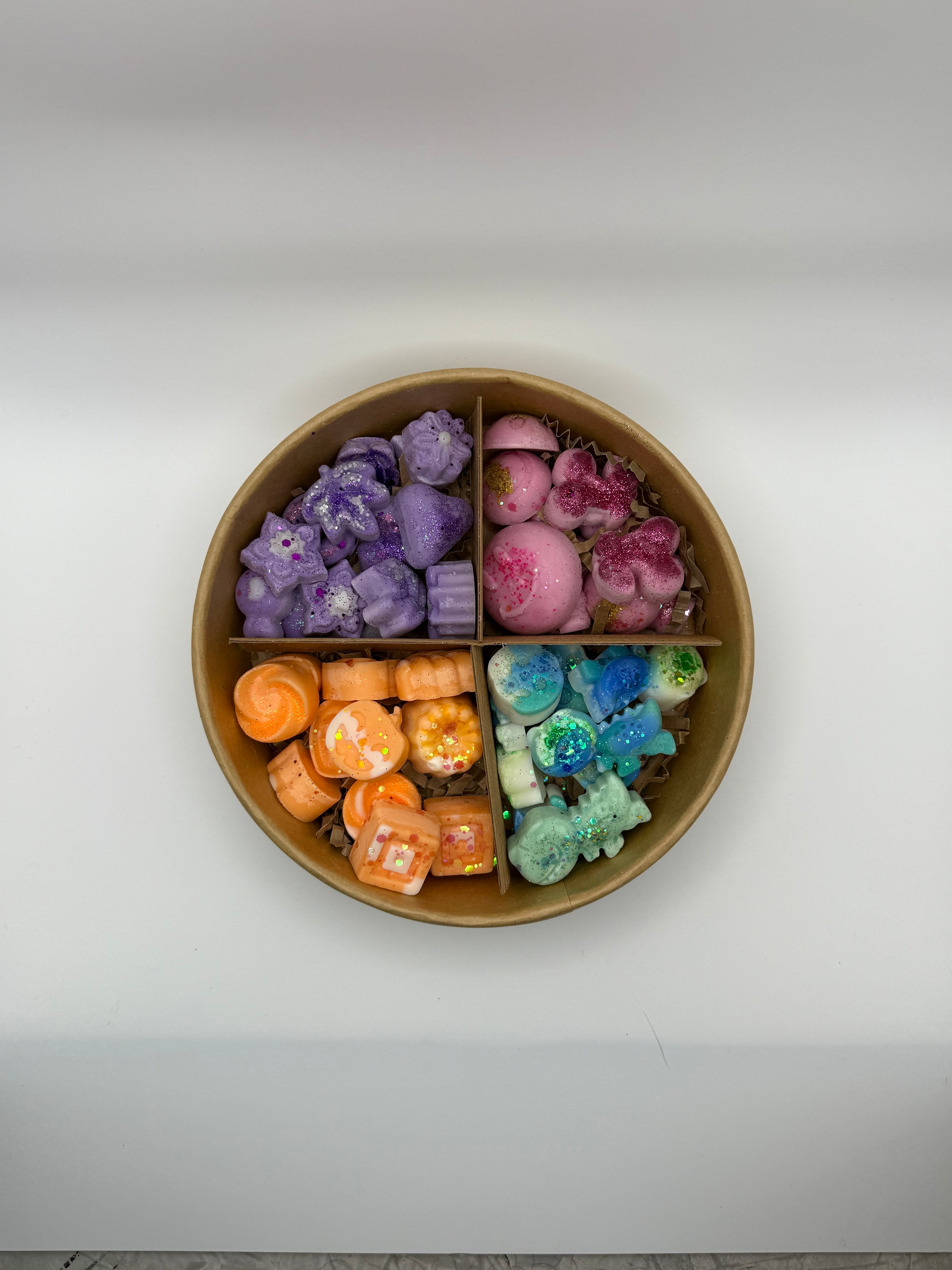 Round container of colorful wax melts on a white background