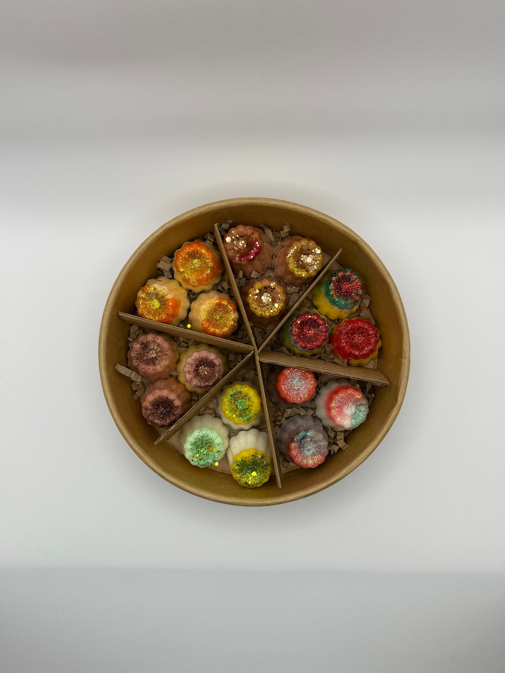 Round container of colorful wax melts on a white background