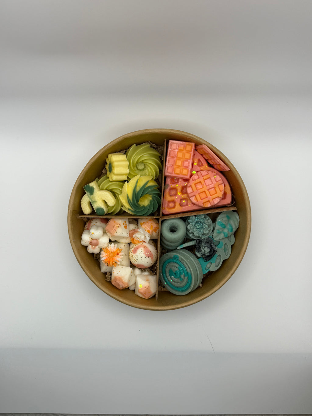Round container of colorful wax melts on a white background